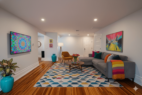 A living room with a grey couch and a blue vase.