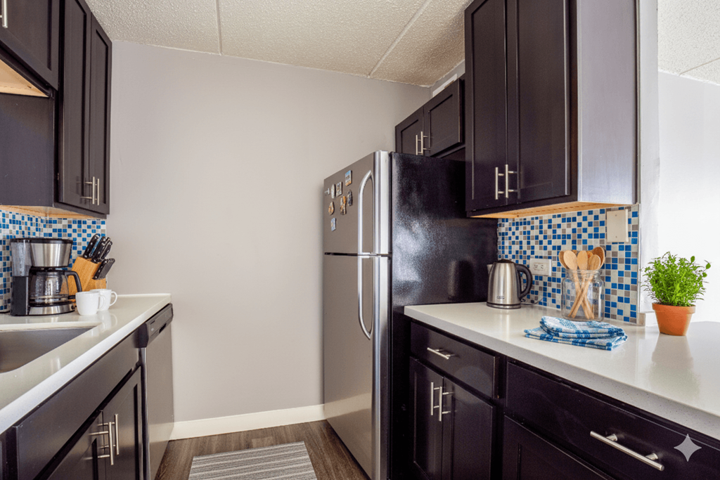 A kitchen with black cabinets and a black fridge.