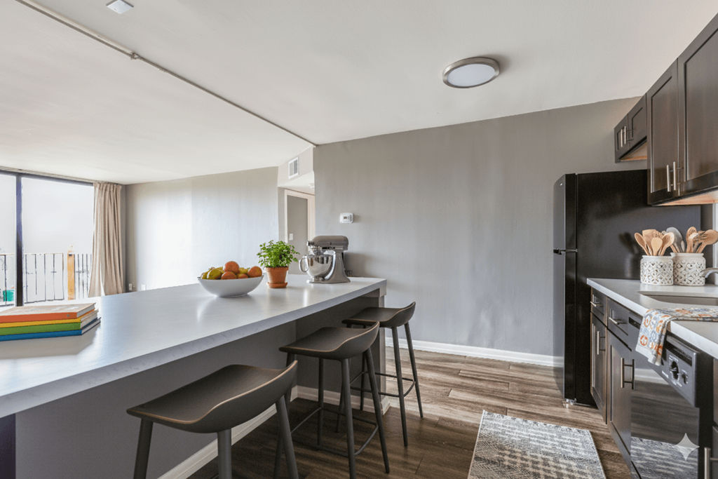 A kitchen with a white countertop and a black refrigerator.