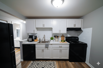 A kitchen with black appliances and white cabinets.