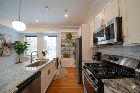A kitchen with a black stove top oven and a black microwave above it.
