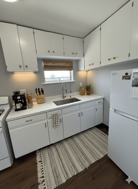 A kitchen with white cabinets and a white fridge.