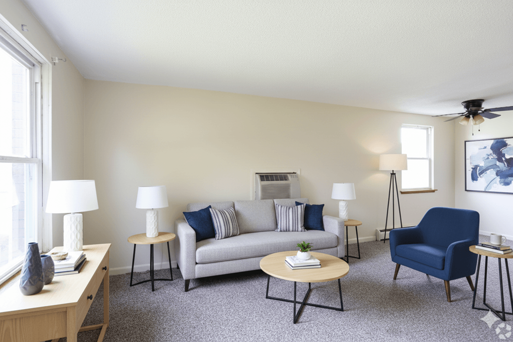 A living room with a grey couch, a blue chair, and a wooden table.