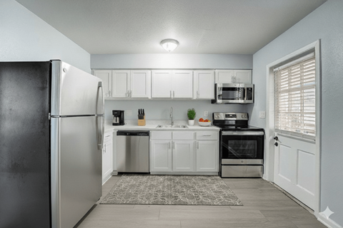 A kitchen with a black refrigerator and white cabinets.
