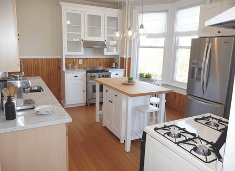 A kitchen with white appliances and wooden floors.
