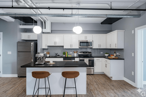 A kitchen with white cabinets and a black countertop.