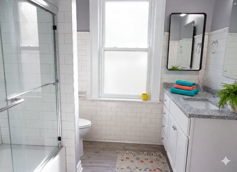 A bathroom with a white tiled shower and a white toilet.
