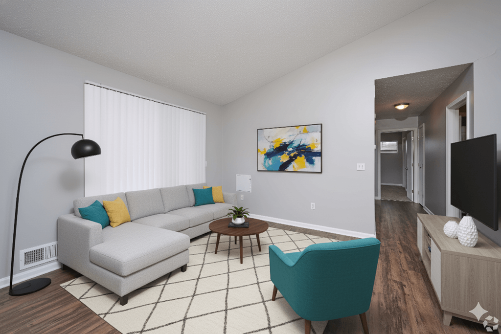 A living room with a grey couch, a green armchair, and a painting on the wall.