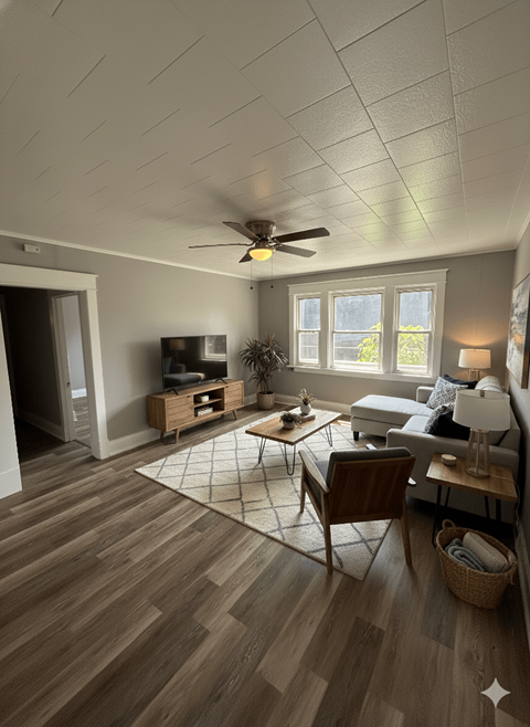 A living room with a ceiling fan and a rug on the floor.
