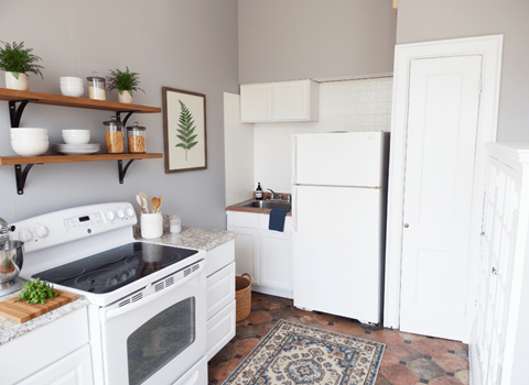 A kitchen with white appliances and a rug on the floor.