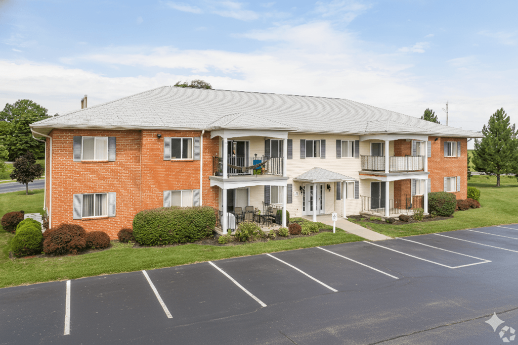 A red brick building with a parking lot in front.