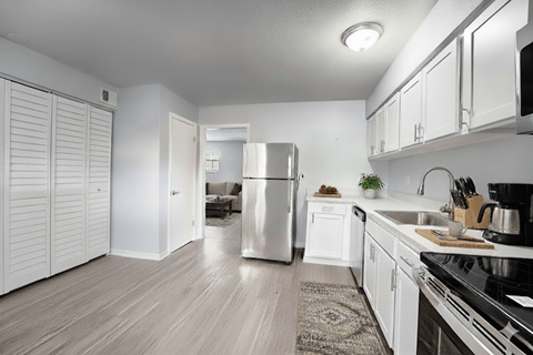 A kitchen with white cabinets and a stainless steel refrigerator.