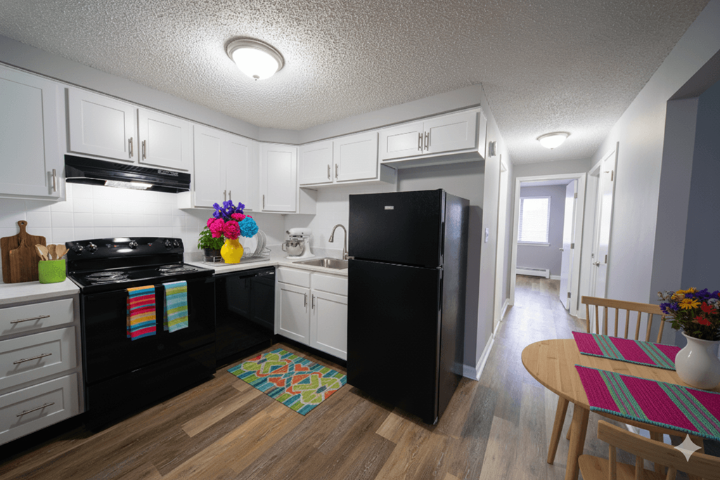 A kitchen with black appliances and white cabinets.