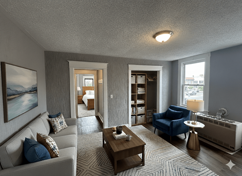 A living room with a grey couch, a blue chair, a coffee table, and a painting on the wall.