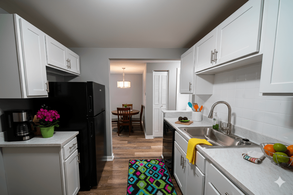 A kitchen with white cabinets and a black refrigerator.