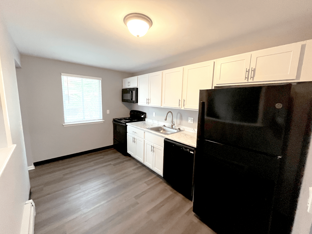 a kitchen with white cabinets and black appliances at Highview Manor Apartments, Fairport, NY, 14450