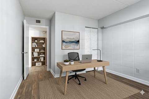 A room with a desk, laptop, and chair.