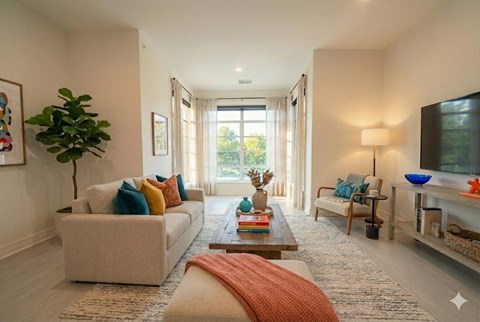 A living room with a white couch, a coffee table, and a large window.