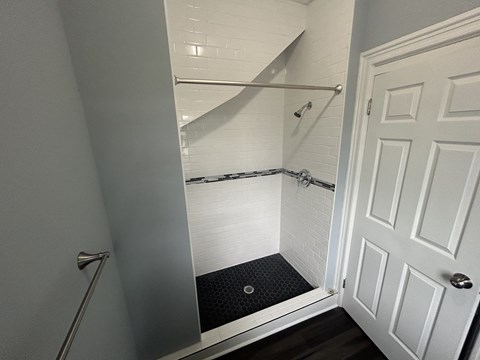 A white door is open to a bathroom with a walk-in shower.