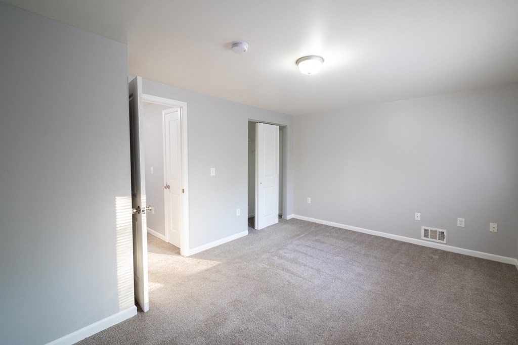 a living room with a carpeted floor and a door to a bedroom at Willowbrooke Apartments, New York, 14420