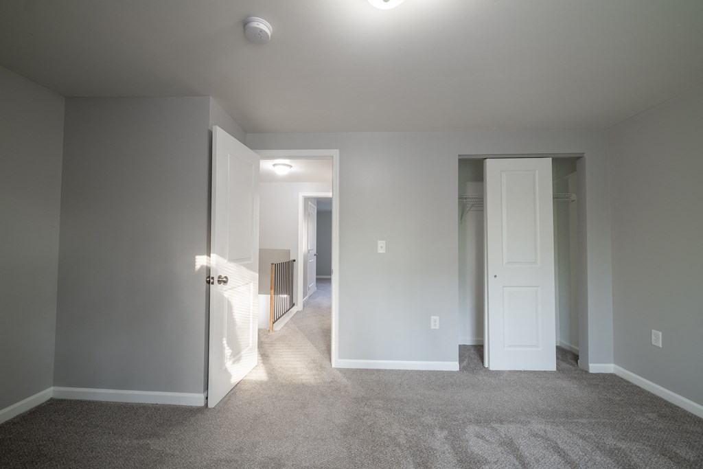 a living room with a carpeted floor and a door to a bedroom at Willowbrooke Apartments, Brockport, NY