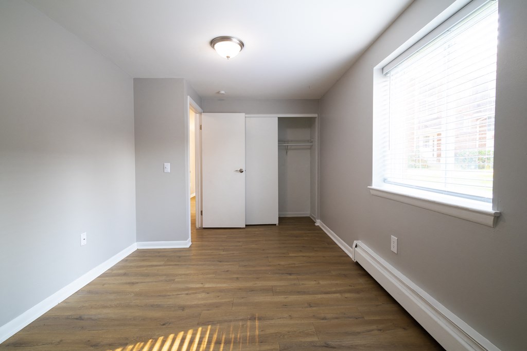 Empty room with wood floors and a large window at Willowbrooke Apartments, Brockport, New York