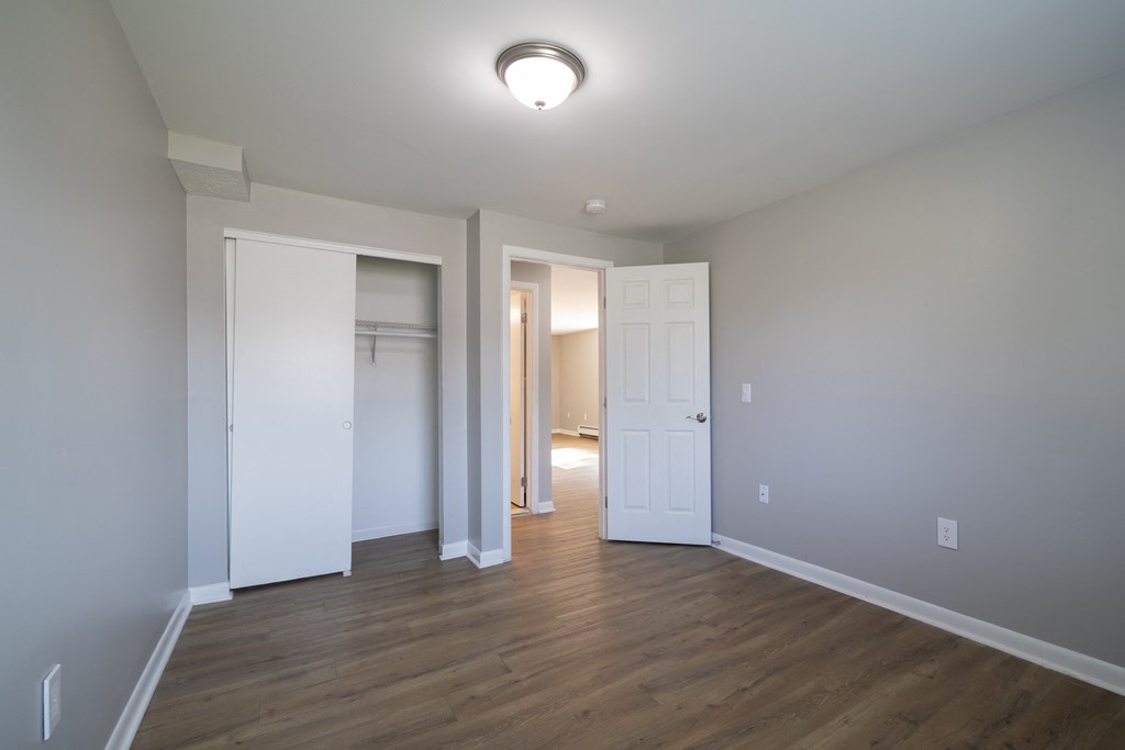 an empty living room with wood flooring and white doors at Willowbrooke Apartments, Brockport, 14420