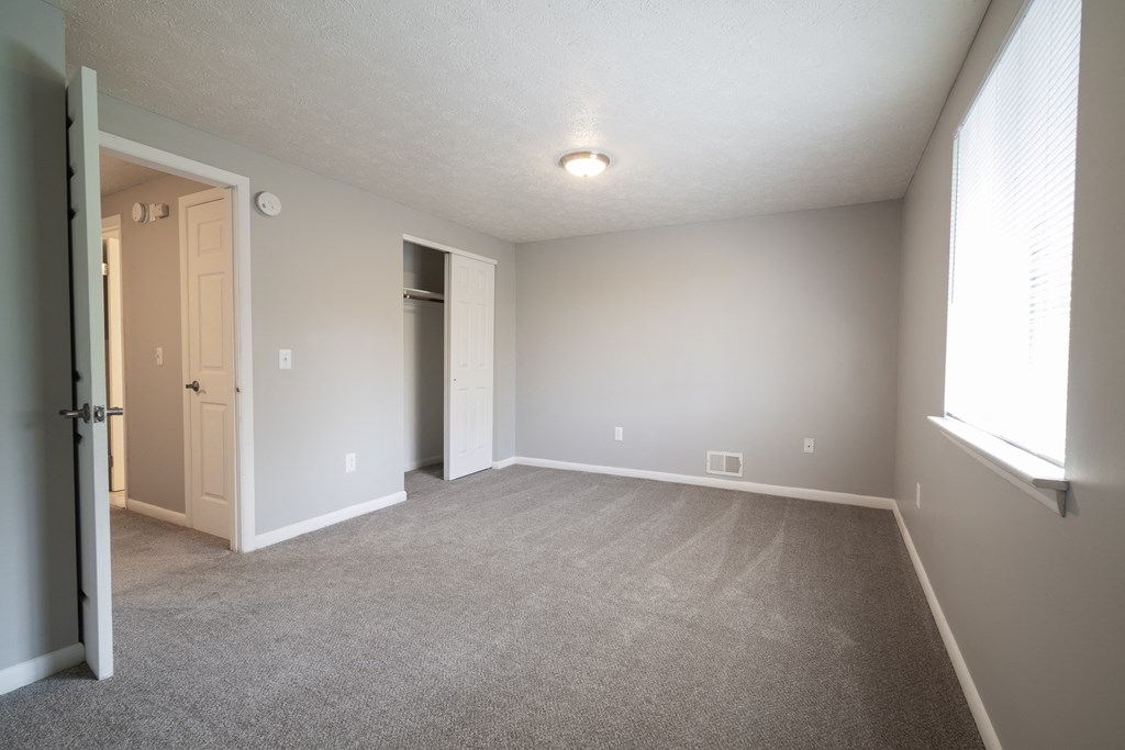 an empty living room with carpet and a door to a closet at Willowbrooke Apartments, New York, 14420