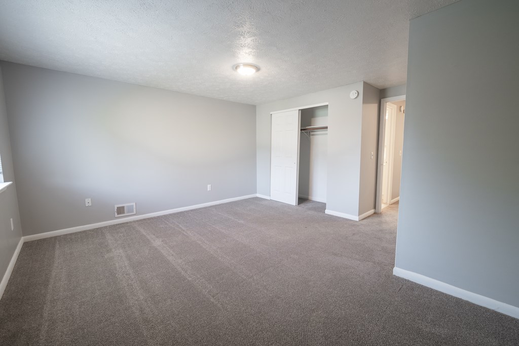 an empty living room with gray carpet and white walls at Willowbrooke Apartments, Brockport, New York