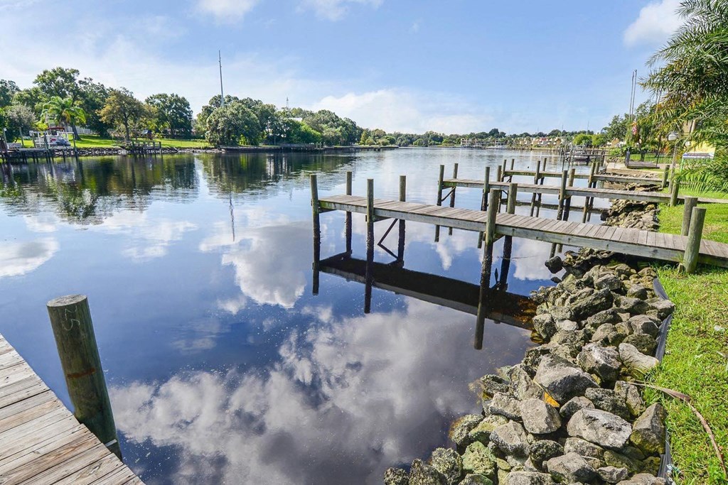 a dock on a lake with a blue sky and clouds reflected in the water