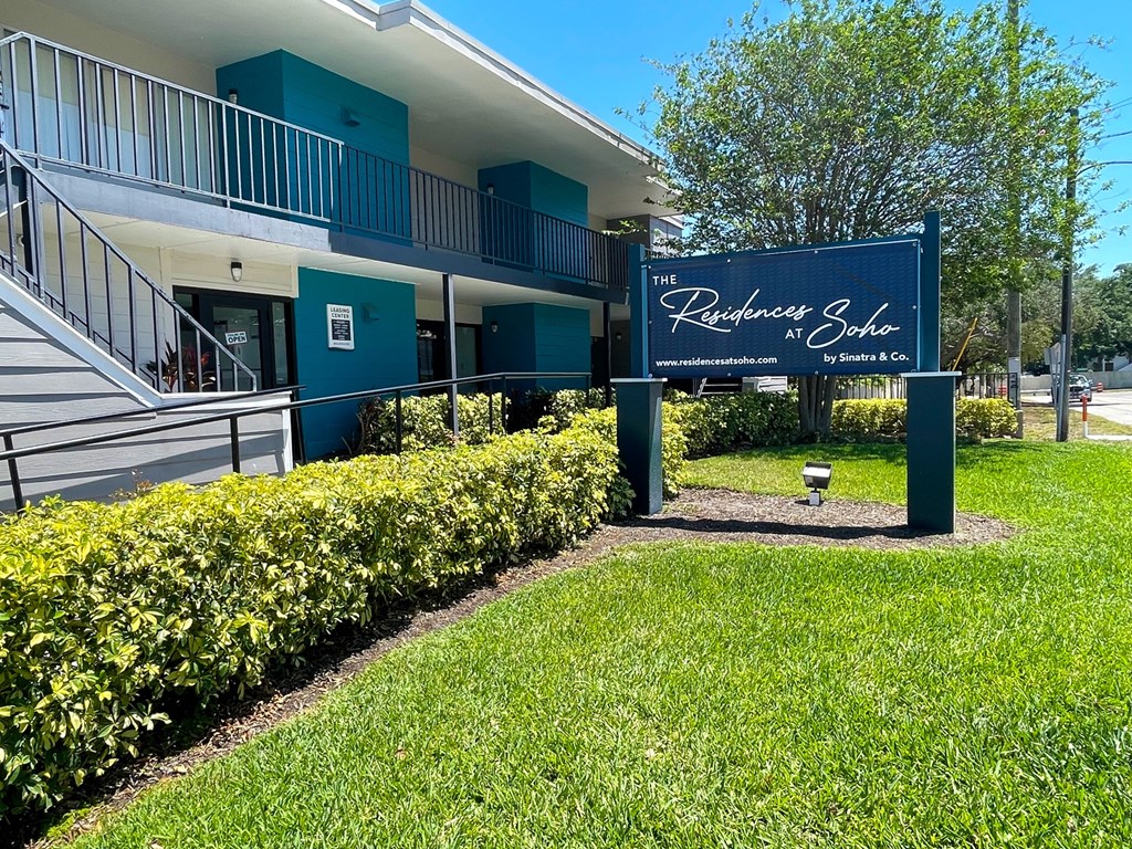 a large blue sign in front of a building with a tree in the background