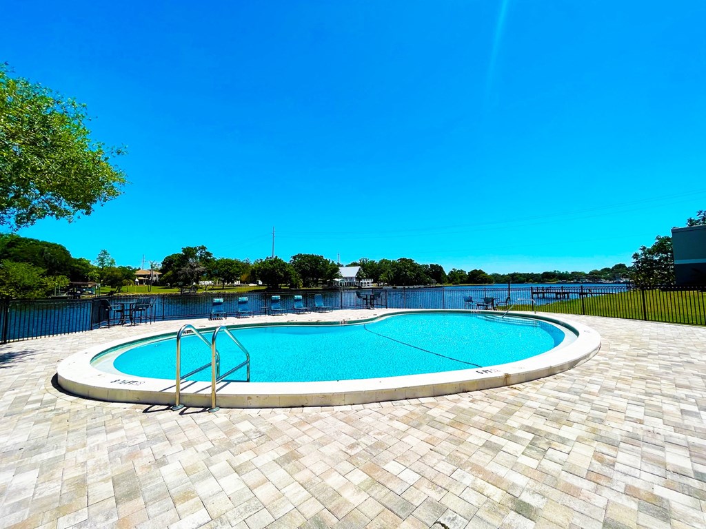 an oval swimming pool with a lake in the background