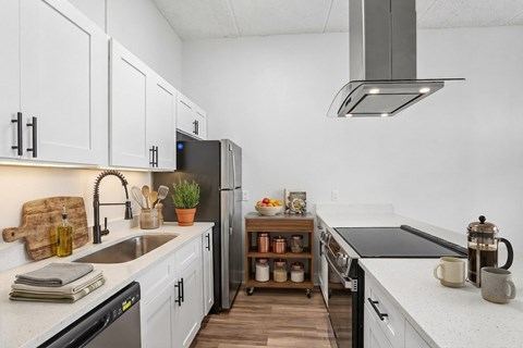 A kitchen with white cabinets and a black refrigerator.