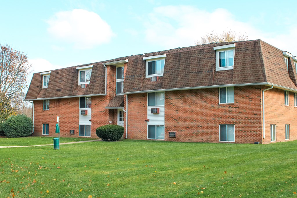 a red brick apartment building with a green lawn at Willowbrooke Apartments, New York