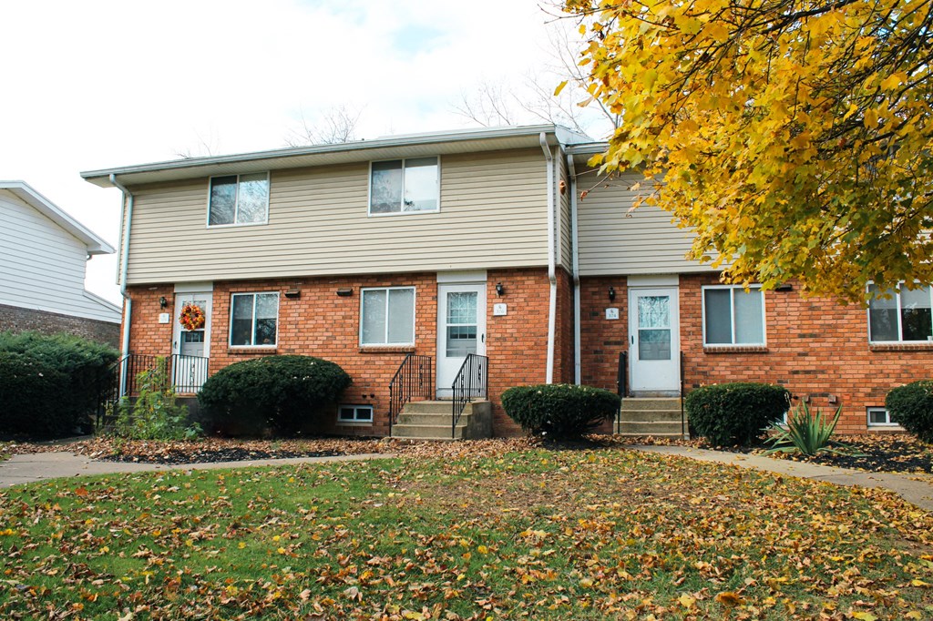 a yellow tree in front of a brick house at Willowbrooke Apartments, Brockport, 14420
