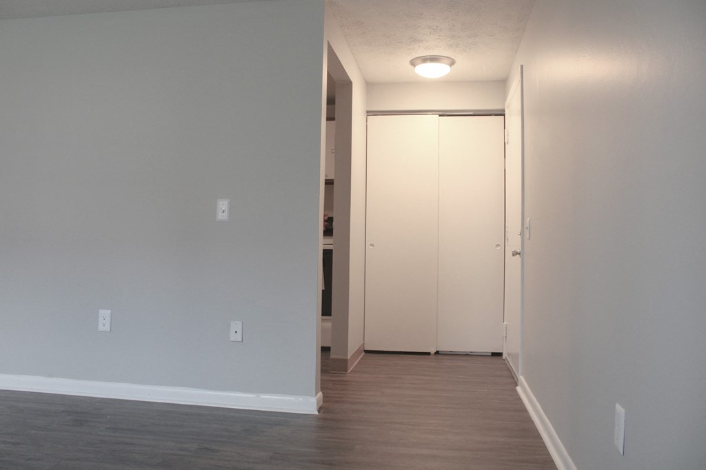 an empty living room with wood floors and a door to a closet at Willowbrooke Apartments, Brockport, New York