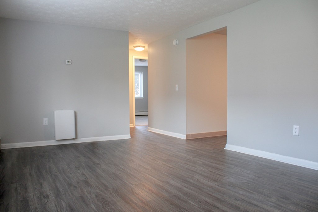 an empty living room with wood floors and white walls at Willowbrooke Apartments, New York