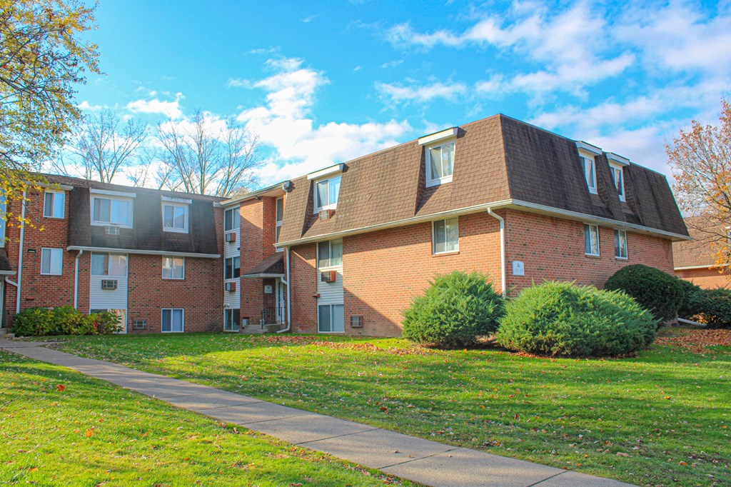 a brick apartment building with a sidewalk in front of it at Willowbrooke Apartments, Brockport, 14420