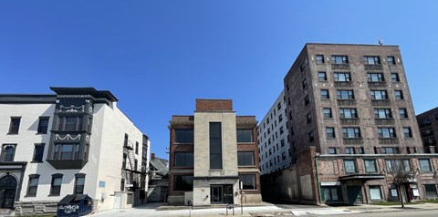 A row of buildings with a white building on the left and a brown building on the right.