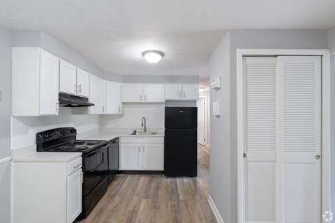 an empty kitchen with white cabinets and black appliances
