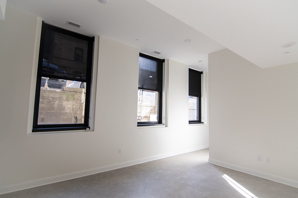 a living room with three windows and white walls