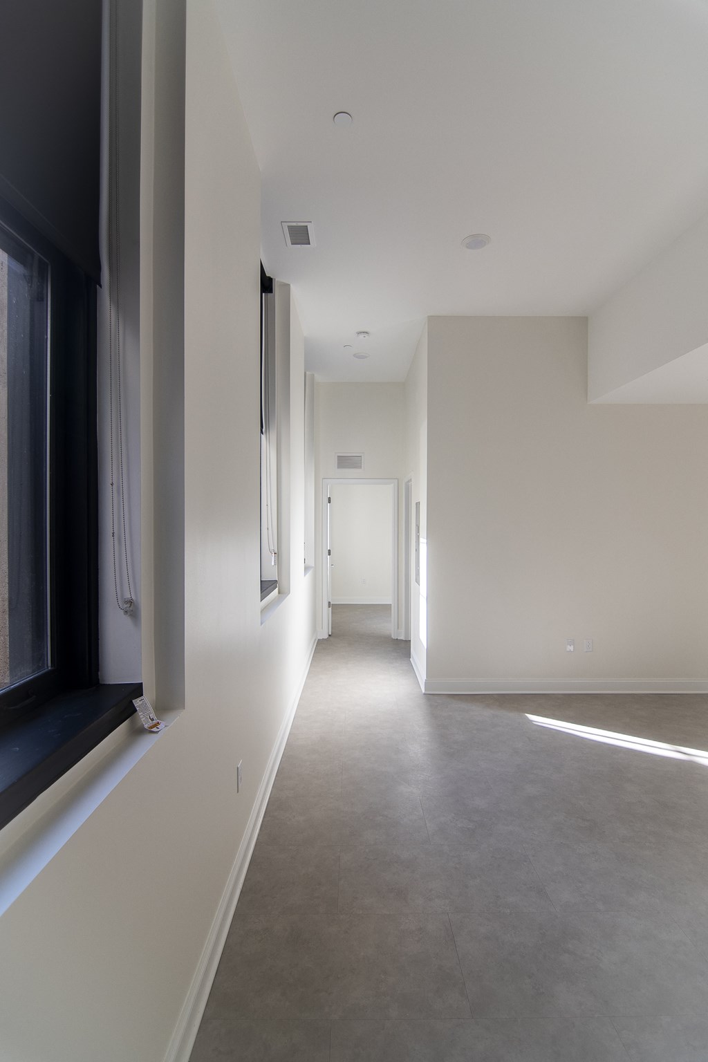 a long hallway with white walls and a window