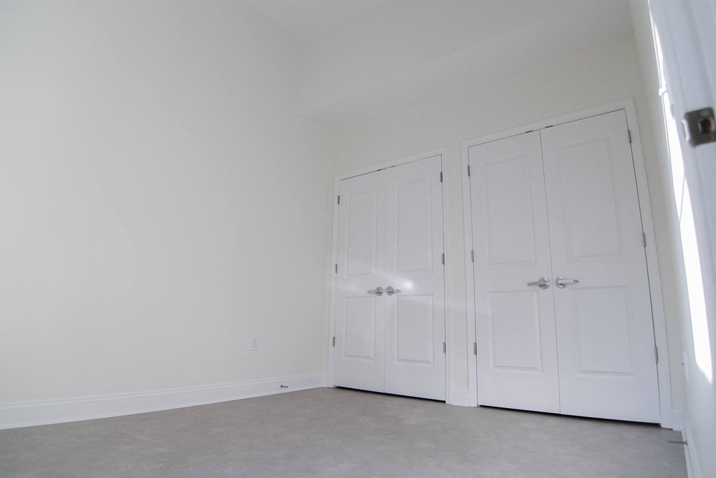 a bedroom with two white doors and a carpeted floor