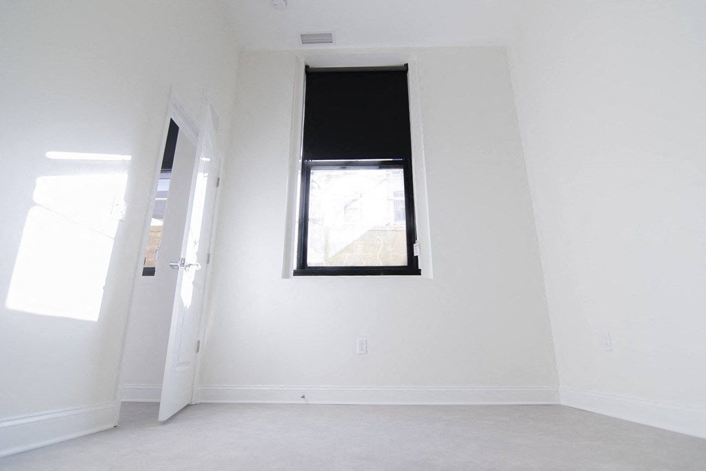 an empty room with a window and white walls
