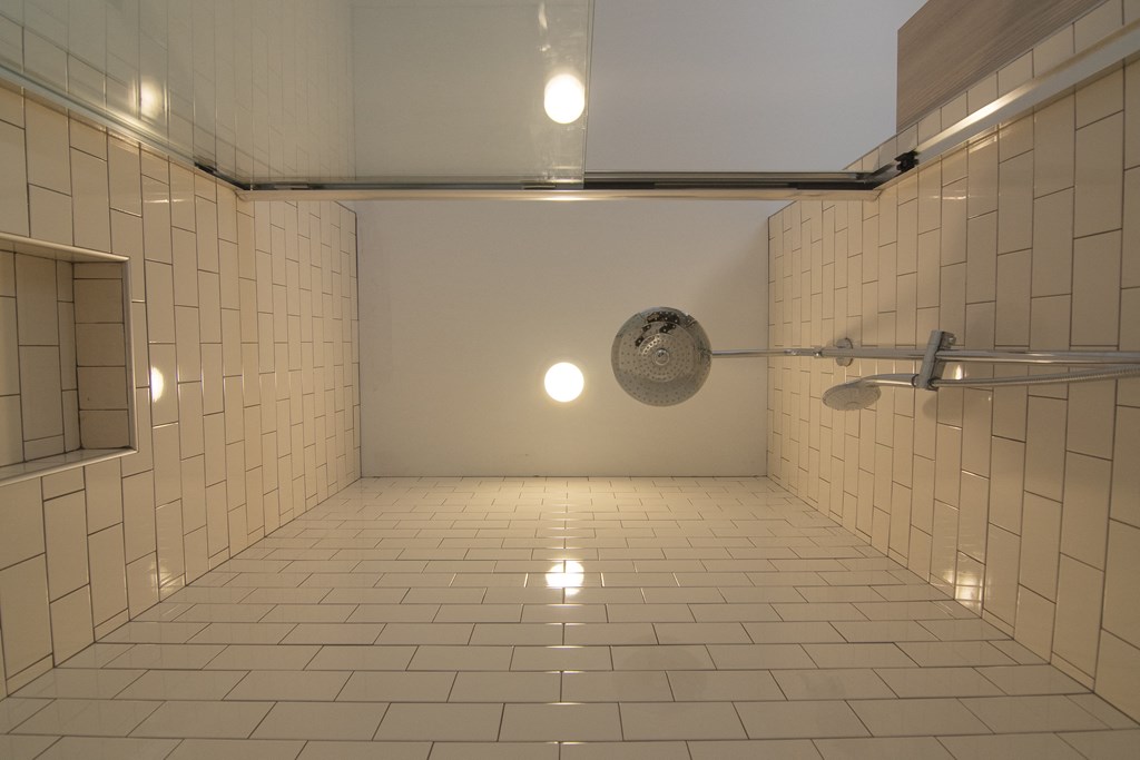 a large white tiled shower in a bathroom with two lights on the ceiling