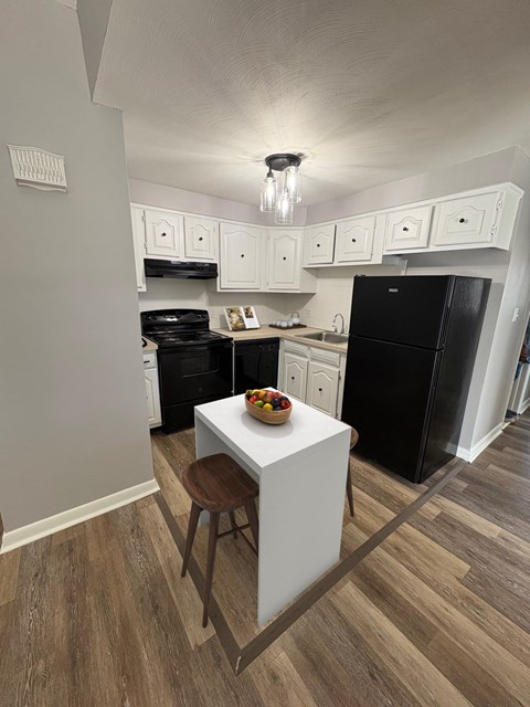 A kitchen with black appliances and white cabinets.