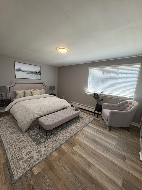 A bedroom with a large bed and a chair.