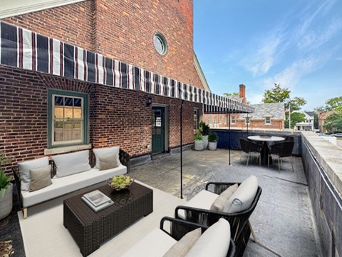 A patio with a table and chairs is set up outside a brick building.