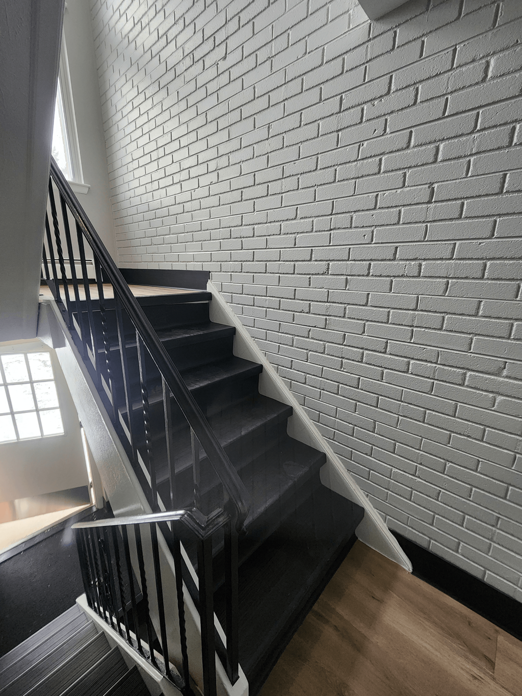 a staircase with black stairs and a white brick wall at Willowbrooke Apartments, New York