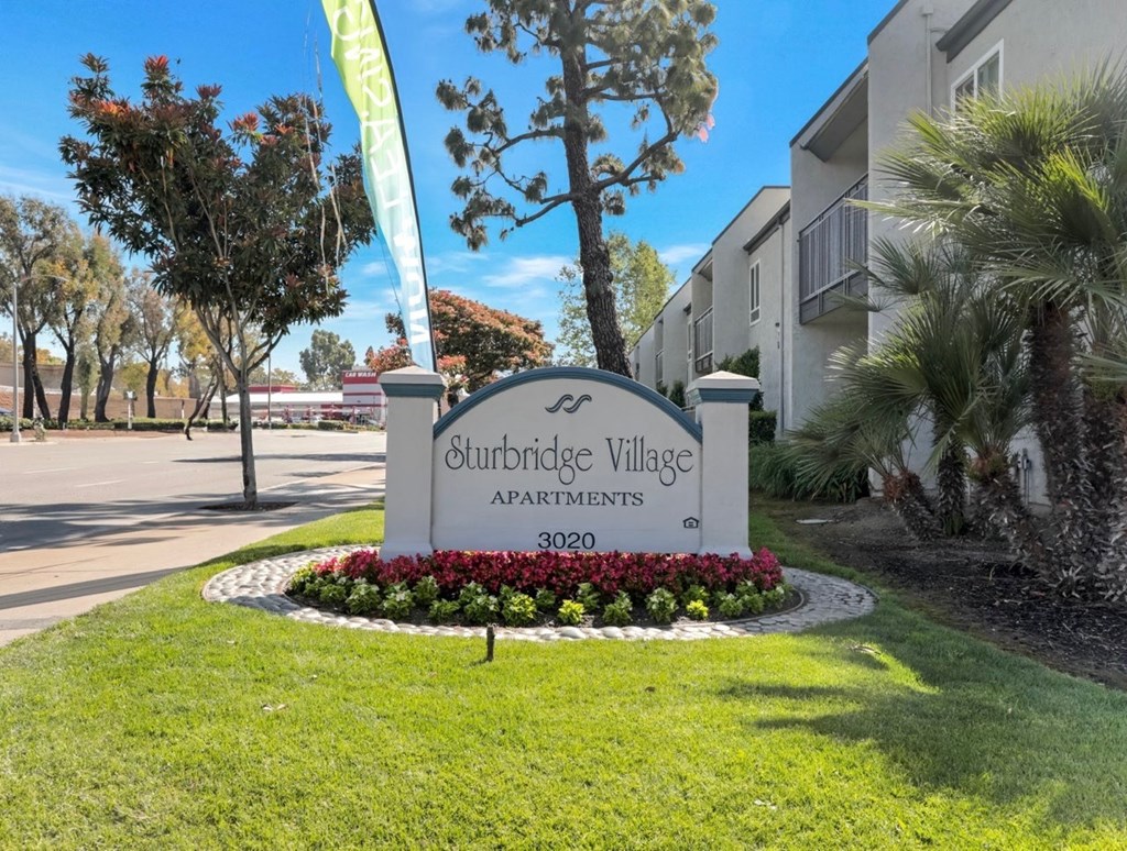 A sign for Sturbridge Village Apartments is in front of a building.